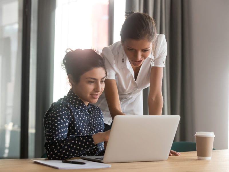 Diverse associates working together using laptop corporate application
