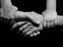 Two Smaller Hands Clutching the Wrists of Two Adult Hands Mid-Handshake