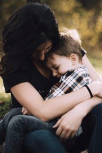 A Woman Putting Her Arms Around A Child Sitting On Her Lap