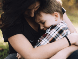 A Woman Putting Her Arms Around A Child Sitting On Her Lap