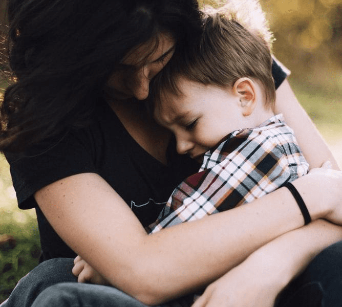 A Woman Putting Her Arms Around A Child Sitting On Her Lap